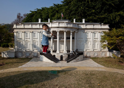 A child poses on the porch of a mock White House at the Window of the World theme park. - Shenzhen, Guangdong