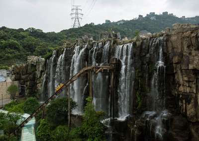 A log chute ride emerges from a fake waterfall at the Knight Valley Eco Park. - Shenzhen, Guangdong