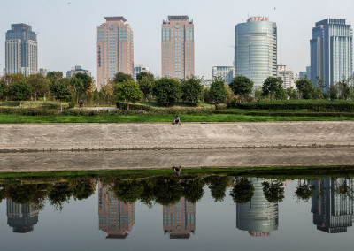 A pedestrian rests alongside a canal outside the new Central Business District. - Zhengzhou, Henan